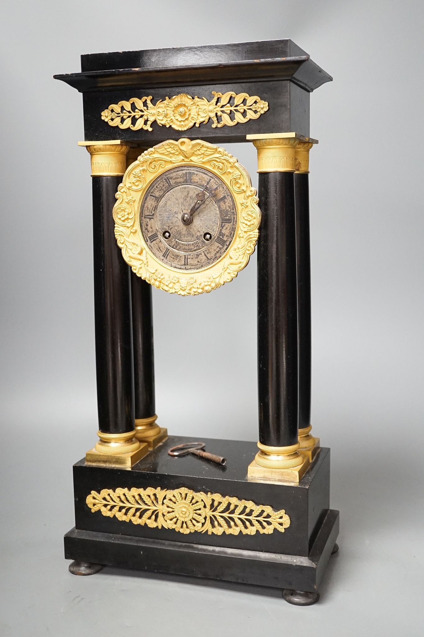 A 19th century ebonised portico mantel clock with brass mounts, 46cms high.